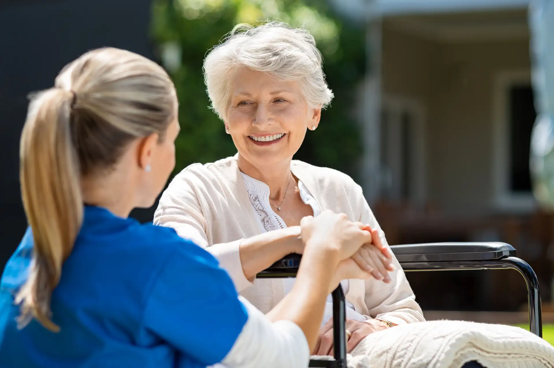 A compassionate caregiver from PureHearts Homes sharing a moment of kindness and support with a smiling elderly woman outdoors, emphasizing personalized care and a nurturing environment.